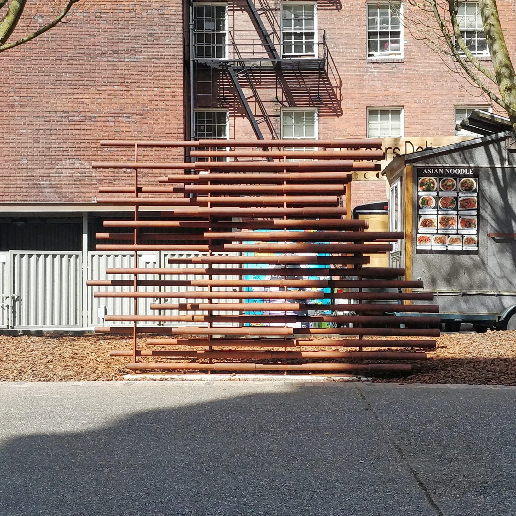 The sculpture on the Portland State campus: rust-red steel pipes stacked on a concrete base, their staggered ends outlining a rider on a bicycle