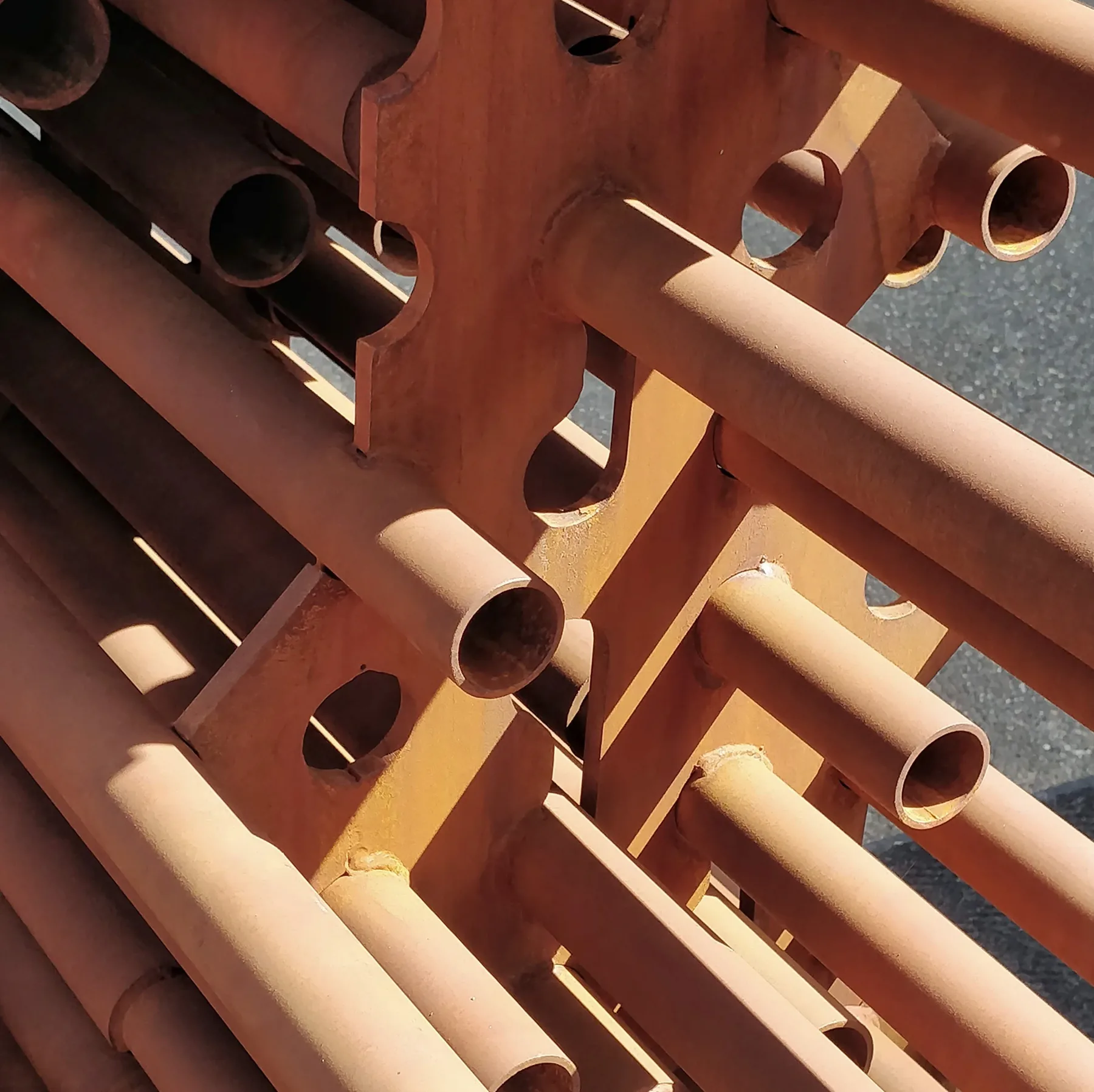 Close view of the rusted pipes threaded through a waterjet-cut steel plate