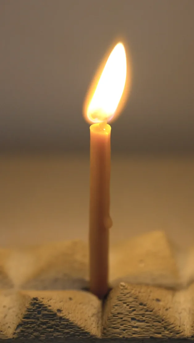 A lit candle standing in the faceted holder