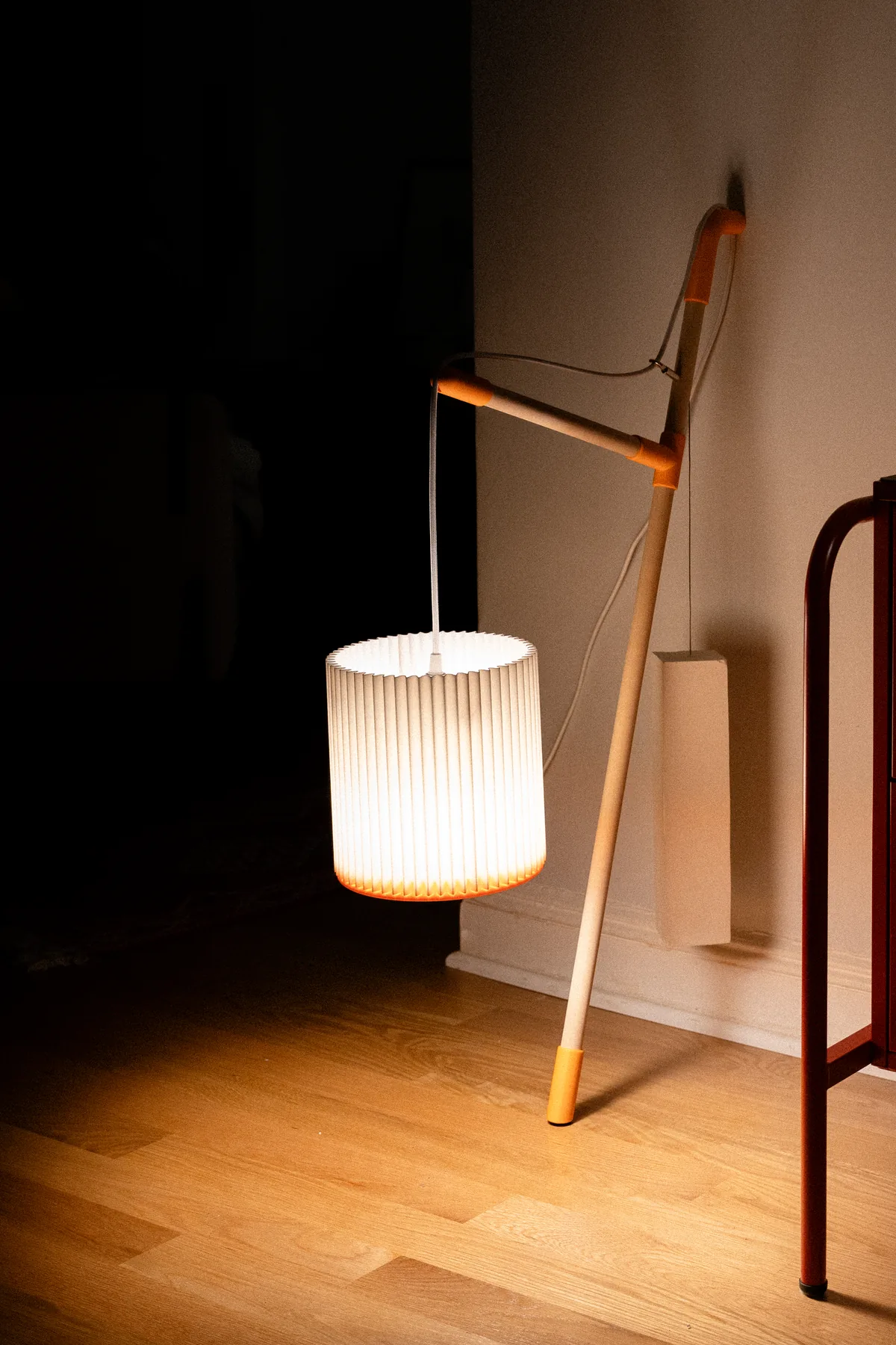 Lean against a wall at night, its pleated paper shade lit