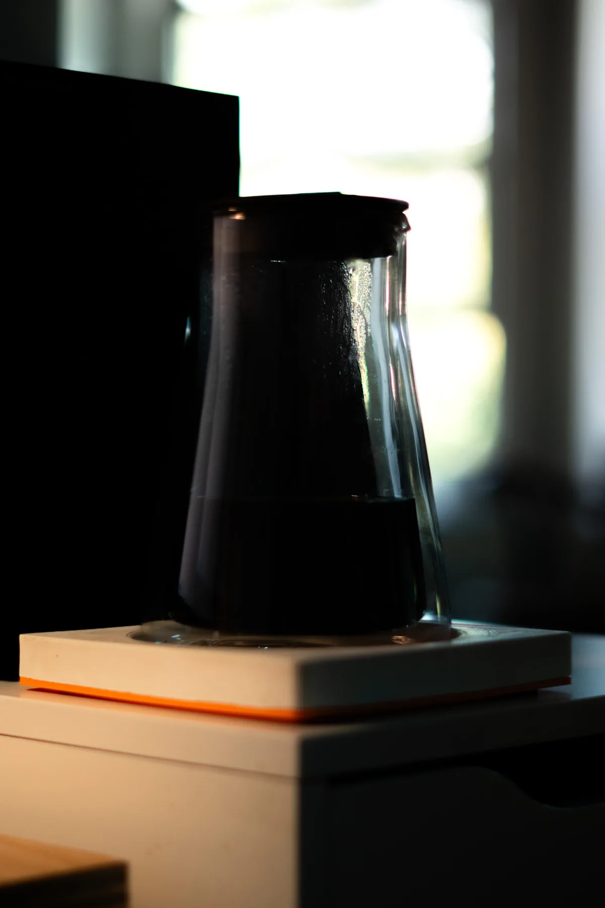 A glass carafe on the pad, its edge glowing orange